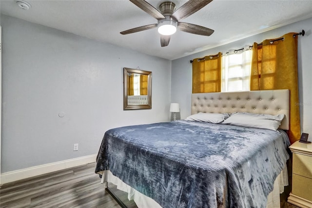 bedroom with dark wood-style floors, ceiling fan, and baseboards