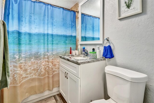 bathroom with vanity, a textured ceiling, hardwood / wood-style flooring, and toilet