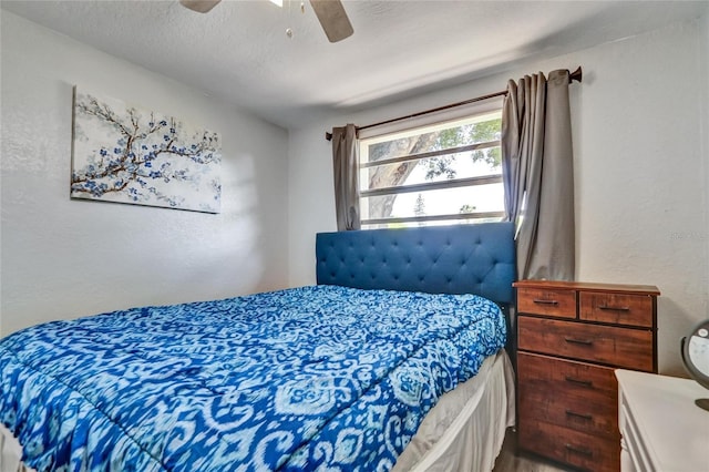 bedroom featuring a textured ceiling, a textured wall, and ceiling fan