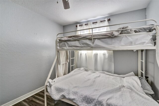 bedroom with a textured ceiling, ceiling fan, and hardwood / wood-style floors