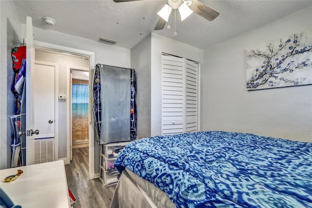 bedroom with visible vents, ceiling fan, wood finished floors, a textured ceiling, and a closet