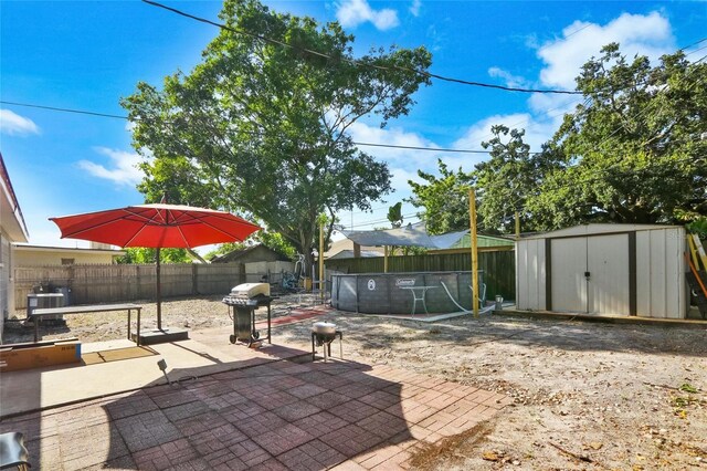 view of patio featuring a fenced backyard, grilling area, an outbuilding, a storage unit, and central air condition unit