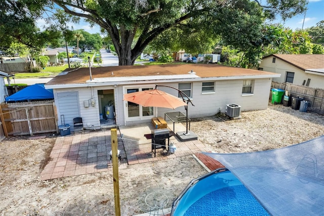 back of property with central AC, a patio area, and a fenced in pool