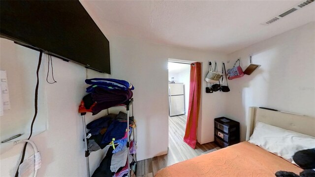 bedroom featuring wood-type flooring and white refrigerator