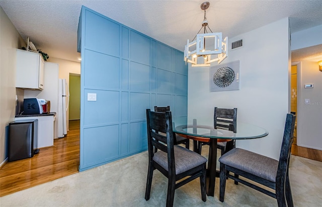 carpeted dining space featuring an inviting chandelier and a textured ceiling