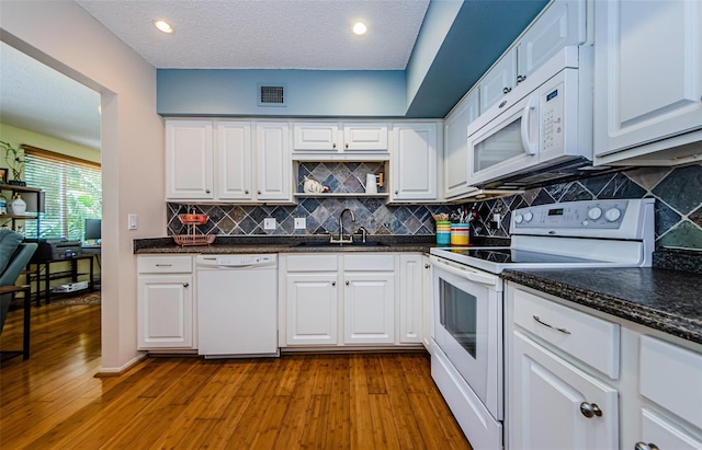 kitchen featuring sink, wood-type flooring, white appliances, and white cabinetry