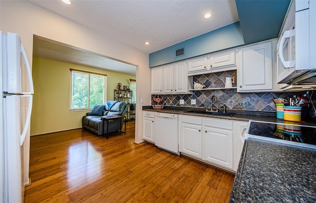 kitchen with white cabinetry, white appliances, backsplash, hardwood / wood-style flooring, and sink