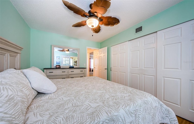 bedroom with a textured ceiling, ceiling fan, wood-type flooring, and a closet