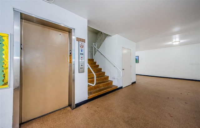 staircase with light carpet and elevator