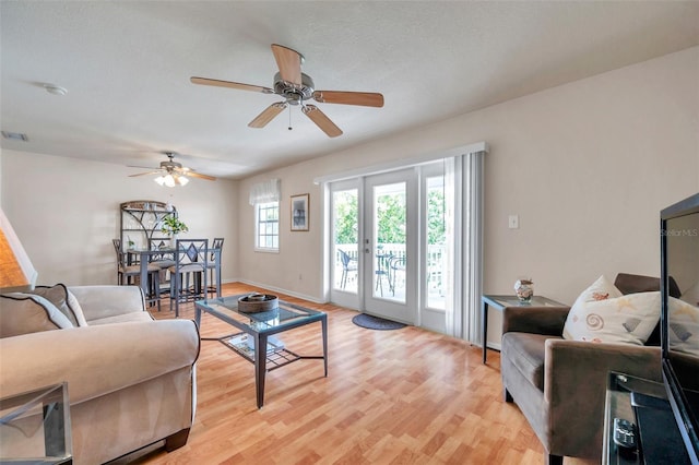 living room featuring french doors, ceiling fan, and light wood-type flooring