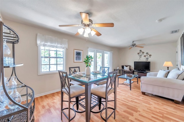 dining space featuring light hardwood / wood-style flooring, a textured ceiling, and plenty of natural light