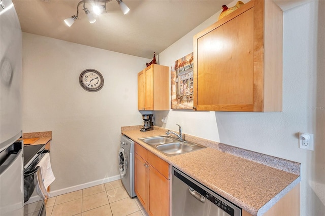 kitchen featuring rail lighting, washer / dryer, sink, light tile patterned floors, and stainless steel dishwasher