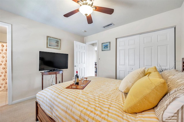 bedroom with connected bathroom, light colored carpet, a closet, and ceiling fan