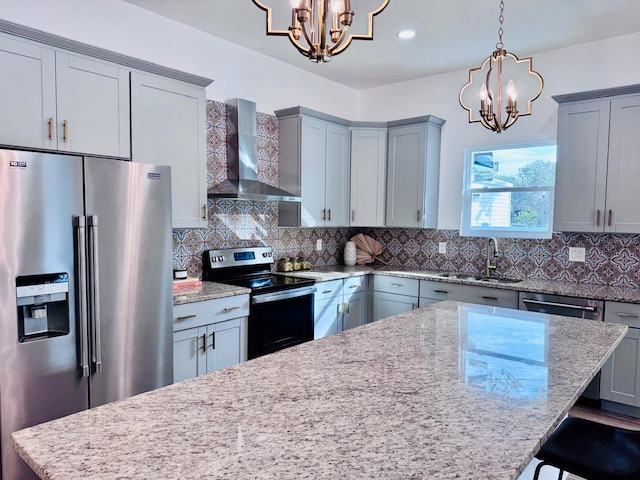 kitchen with stainless steel appliances, sink, a chandelier, and wall chimney range hood