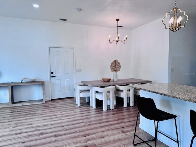 dining area with light hardwood / wood-style floors and an inviting chandelier