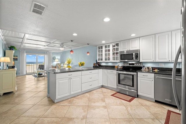 kitchen featuring light tile patterned floors, visible vents, dark countertops, appliances with stainless steel finishes, and a peninsula