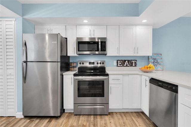 kitchen with stainless steel appliances, light hardwood / wood-style floors, and white cabinets