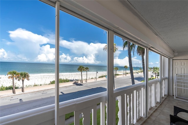 unfurnished sunroom featuring a water view and a view of the beach