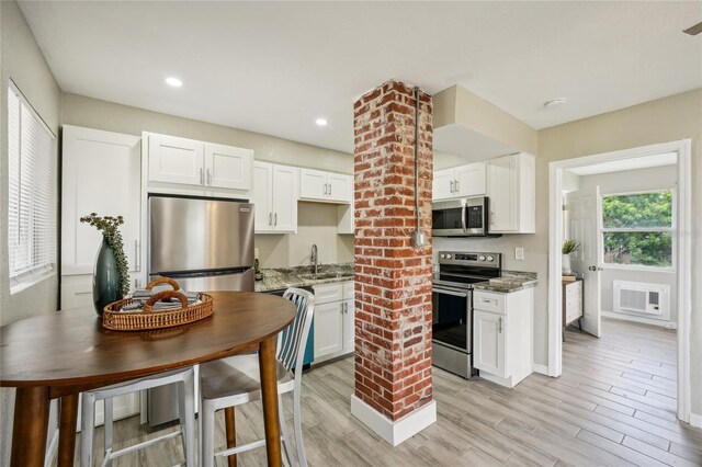 kitchen featuring stainless steel appliances, sink, dark stone countertops, and white cabinets