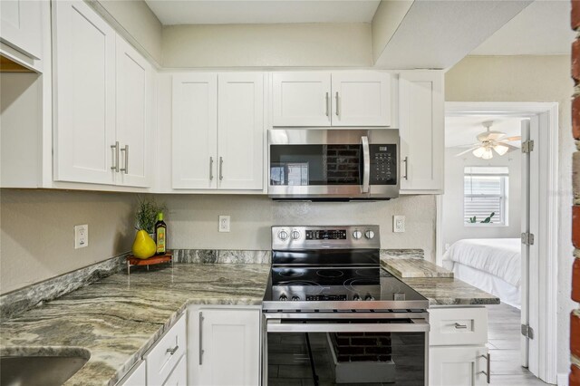 kitchen with light stone counters, ceiling fan, appliances with stainless steel finishes, and white cabinets