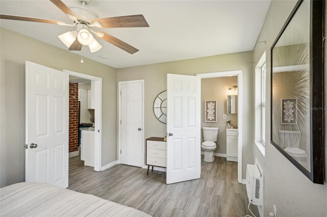 bedroom featuring ensuite bathroom, a wall mounted air conditioner, ceiling fan, and light wood-type flooring