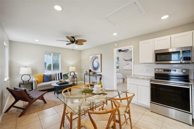 kitchen featuring stainless steel appliances, light tile patterned floors, decorative backsplash, and white cabinets