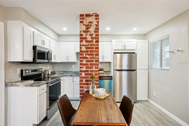 kitchen with white cabinetry, light stone countertops, appliances with stainless steel finishes, and light wood-type flooring