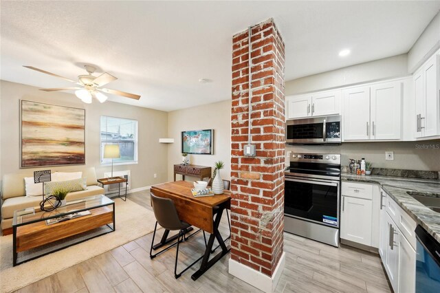 kitchen with light wood-type flooring, light stone countertops, white cabinets, and appliances with stainless steel finishes