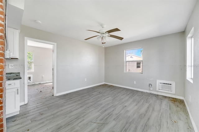 empty room with light hardwood / wood-style flooring, plenty of natural light, a wall unit AC, and ceiling fan