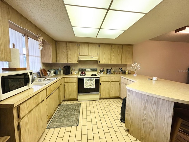 kitchen featuring white appliances, kitchen peninsula, sink, a breakfast bar area, and light brown cabinets