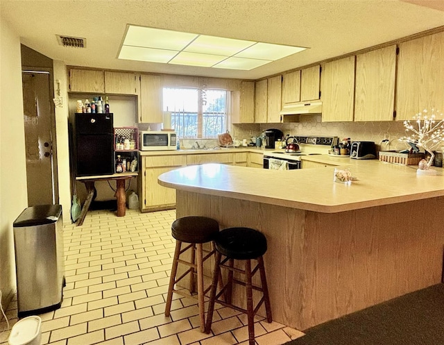 kitchen featuring white appliances, light brown cabinetry, backsplash, a breakfast bar, and kitchen peninsula