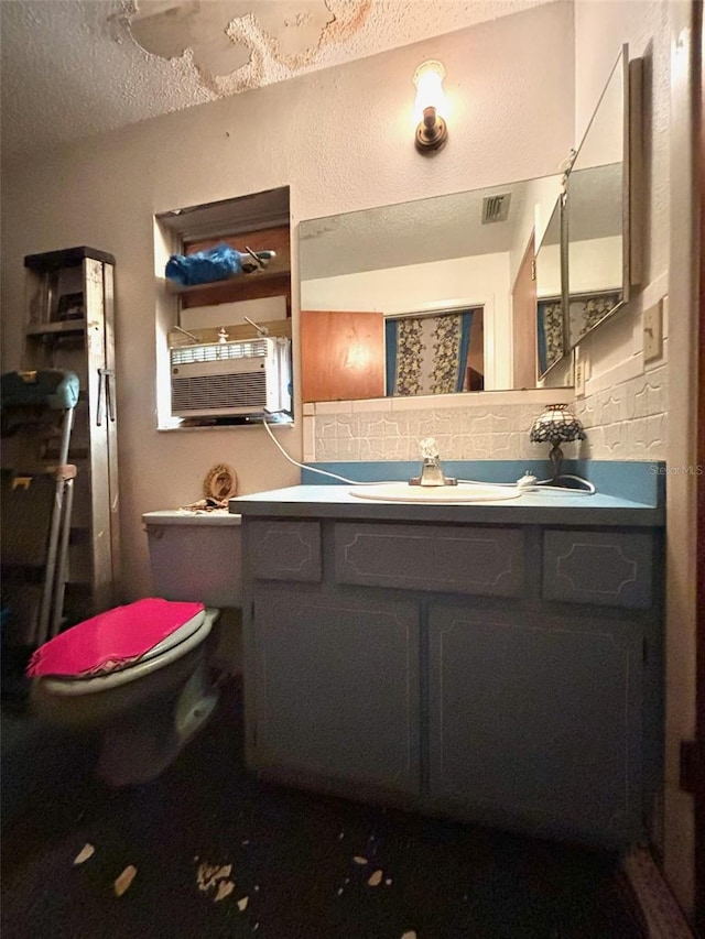 bathroom with a textured ceiling, vanity, toilet, and decorative backsplash