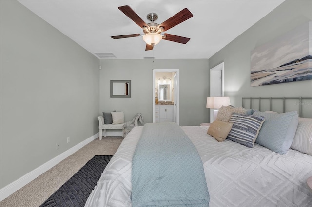 bedroom with ceiling fan, light colored carpet, and ensuite bath