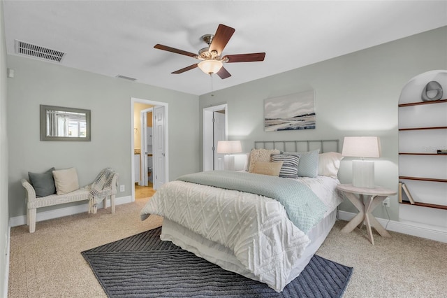 bedroom with ceiling fan, ensuite bathroom, and light colored carpet