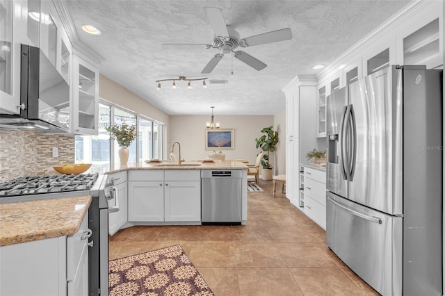 kitchen featuring appliances with stainless steel finishes, a textured ceiling, white cabinets, decorative light fixtures, and sink