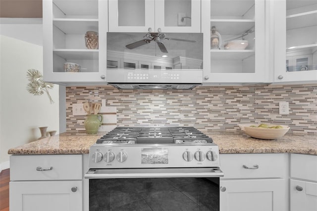 kitchen with light stone countertops, stainless steel gas range, white cabinetry, backsplash, and ceiling fan