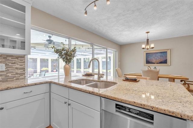 kitchen featuring sink, backsplash, white cabinetry, light stone countertops, and a textured ceiling