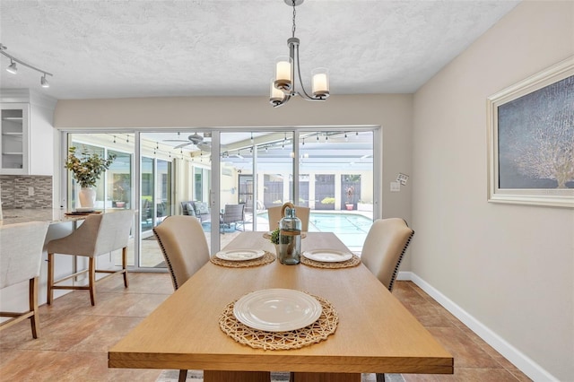 dining room with ceiling fan with notable chandelier and a textured ceiling