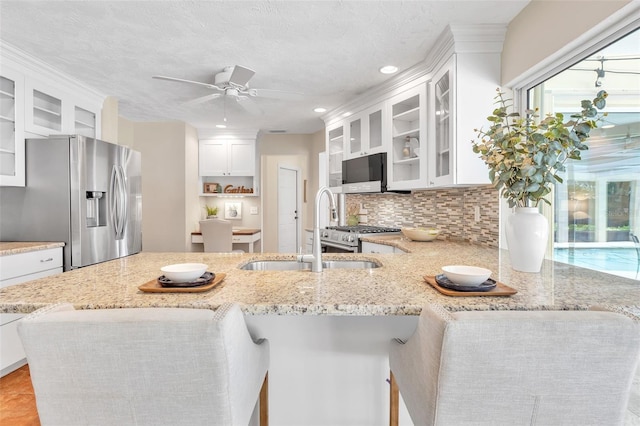 kitchen with white cabinetry, kitchen peninsula, light stone countertops, and stainless steel fridge