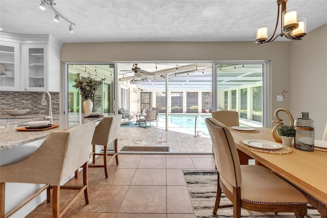 tiled dining room featuring ceiling fan, sink, and a textured ceiling