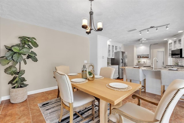 dining space with sink, ceiling fan with notable chandelier, a textured ceiling, and light tile patterned flooring