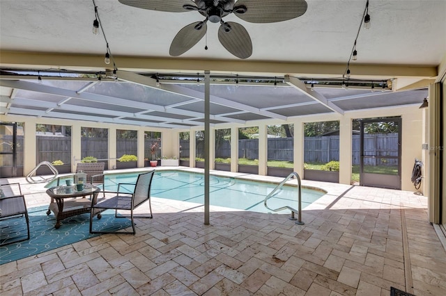 view of swimming pool featuring glass enclosure, a patio area, and ceiling fan