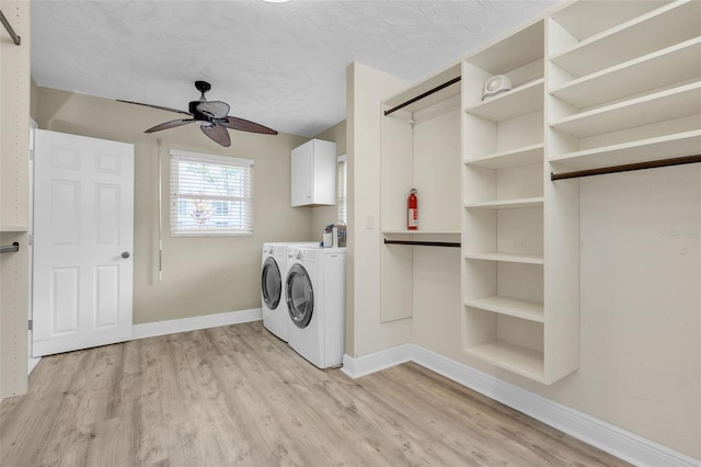 clothes washing area with a textured ceiling, light hardwood / wood-style flooring, washing machine and dryer, ceiling fan, and cabinets