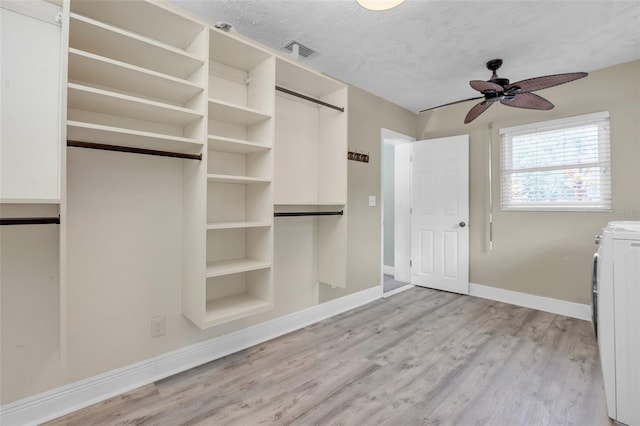 spacious closet featuring ceiling fan, washer / clothes dryer, and light hardwood / wood-style floors