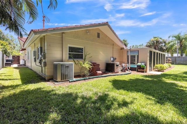 rear view of house featuring central AC and a yard