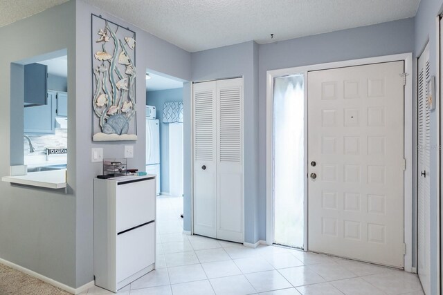 entrance foyer with sink, light tile patterned floors, and a textured ceiling