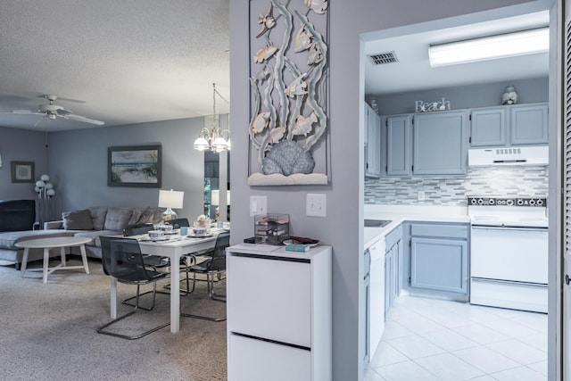 kitchen featuring tasteful backsplash, white appliances, pendant lighting, light colored carpet, and ceiling fan with notable chandelier