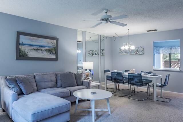 living room featuring ceiling fan with notable chandelier, carpet, and a textured ceiling