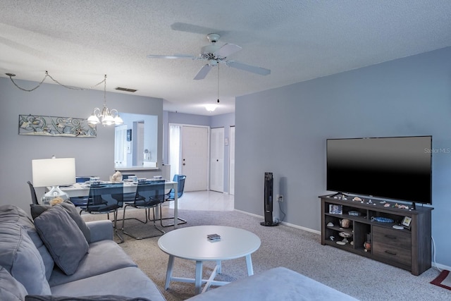 living room with a textured ceiling, light colored carpet, and ceiling fan with notable chandelier