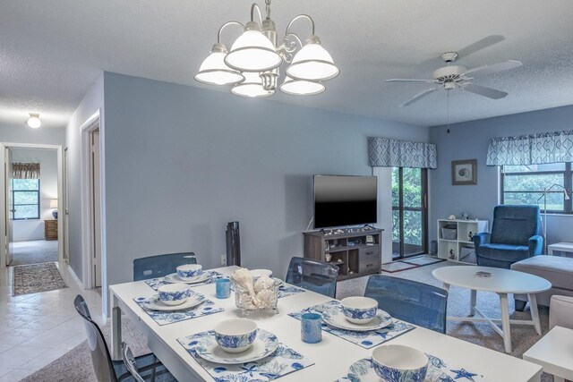 dining area featuring a textured ceiling, ceiling fan with notable chandelier, and light colored carpet